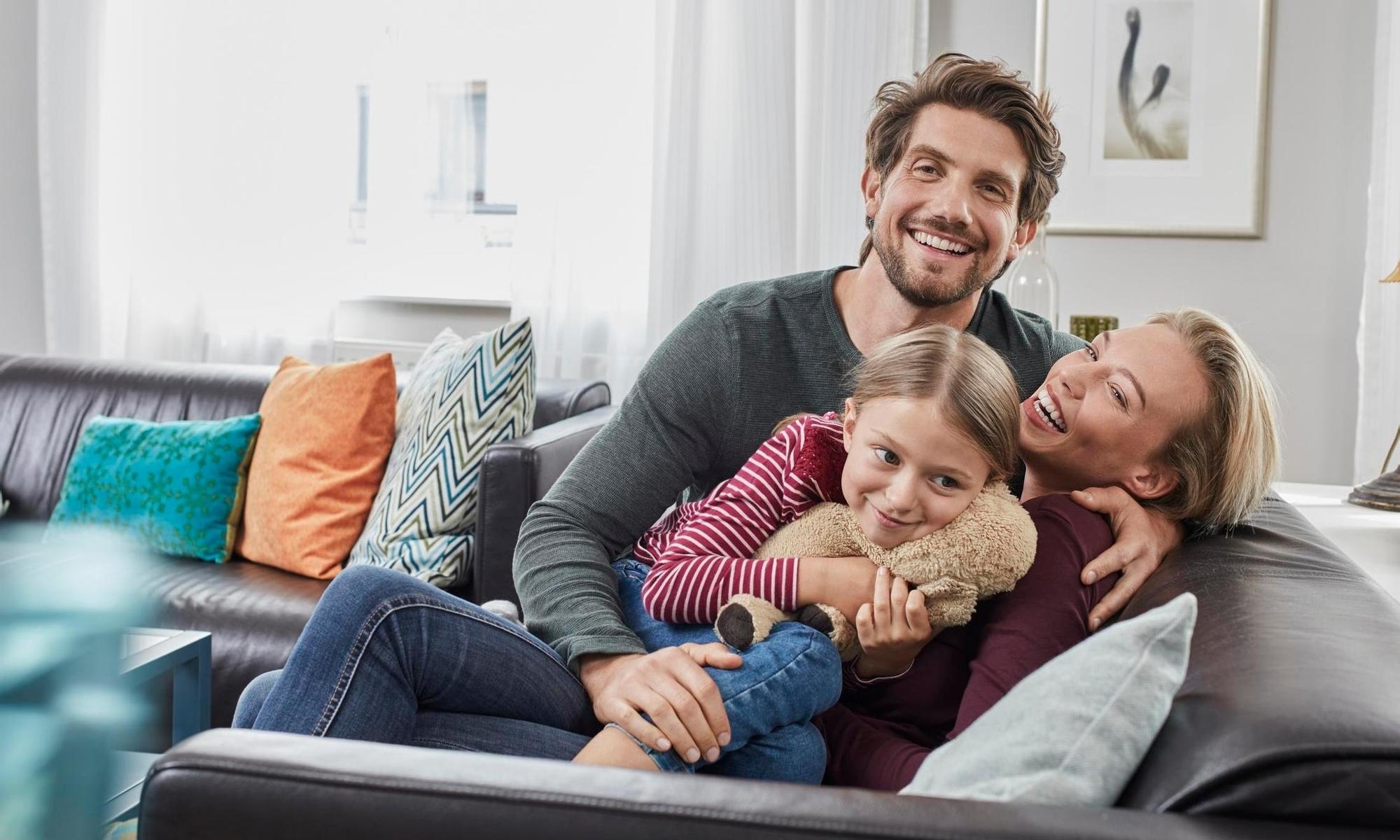 Glad familj kramas hemma i en soffa