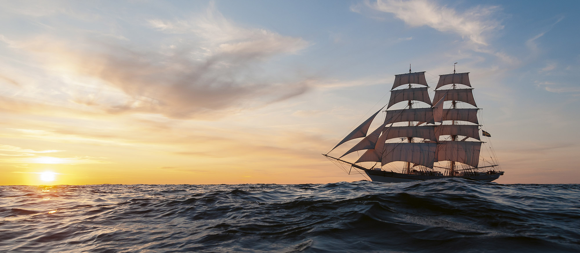 Briggen Tre Kroner seglar i solnedgången
