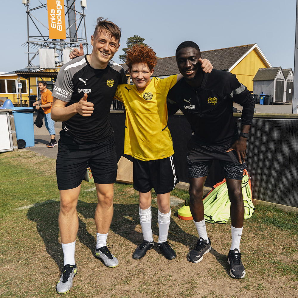  Två spelare från Mjällbys A-trupp håller armarna om Jakob som spelar i Allstars