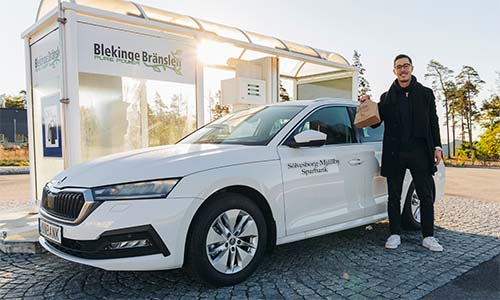 Oscar står framför bankens biogasbil vid en tankstation.