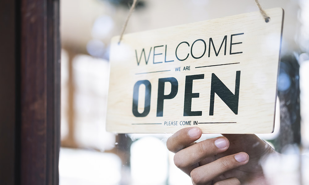 En skylt i ett fönster visar texten Open