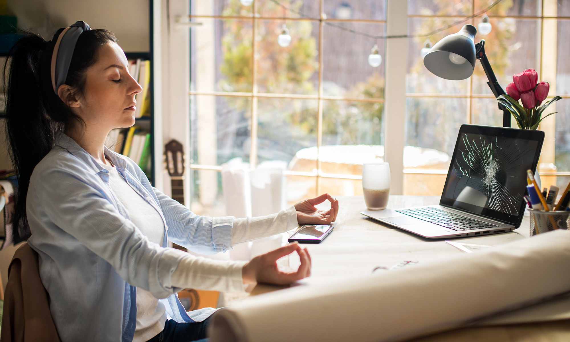 Kvinna mediterar framför sin spruckna laptop