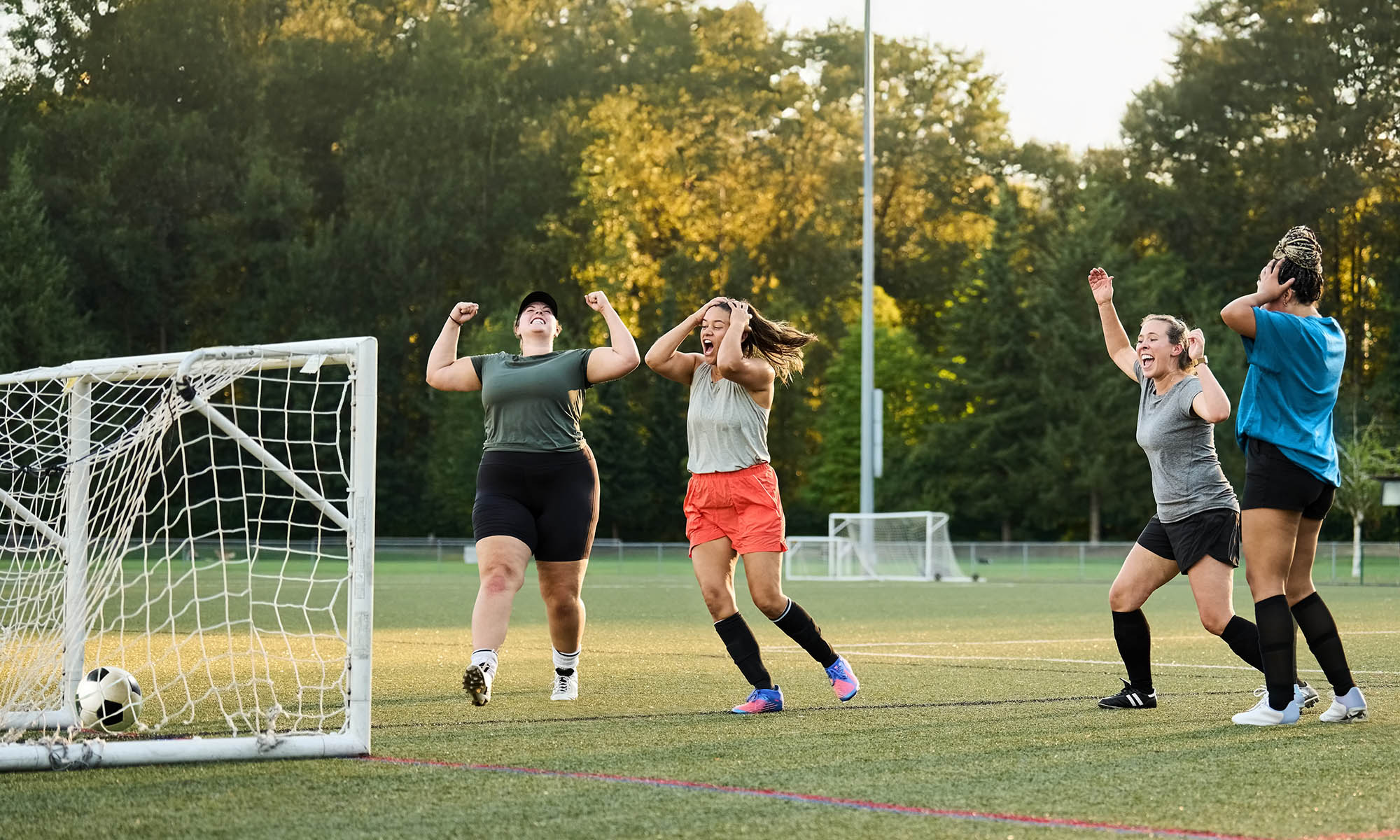 Group of female soccer players celebrating a goal during team practice session on outdoors field
